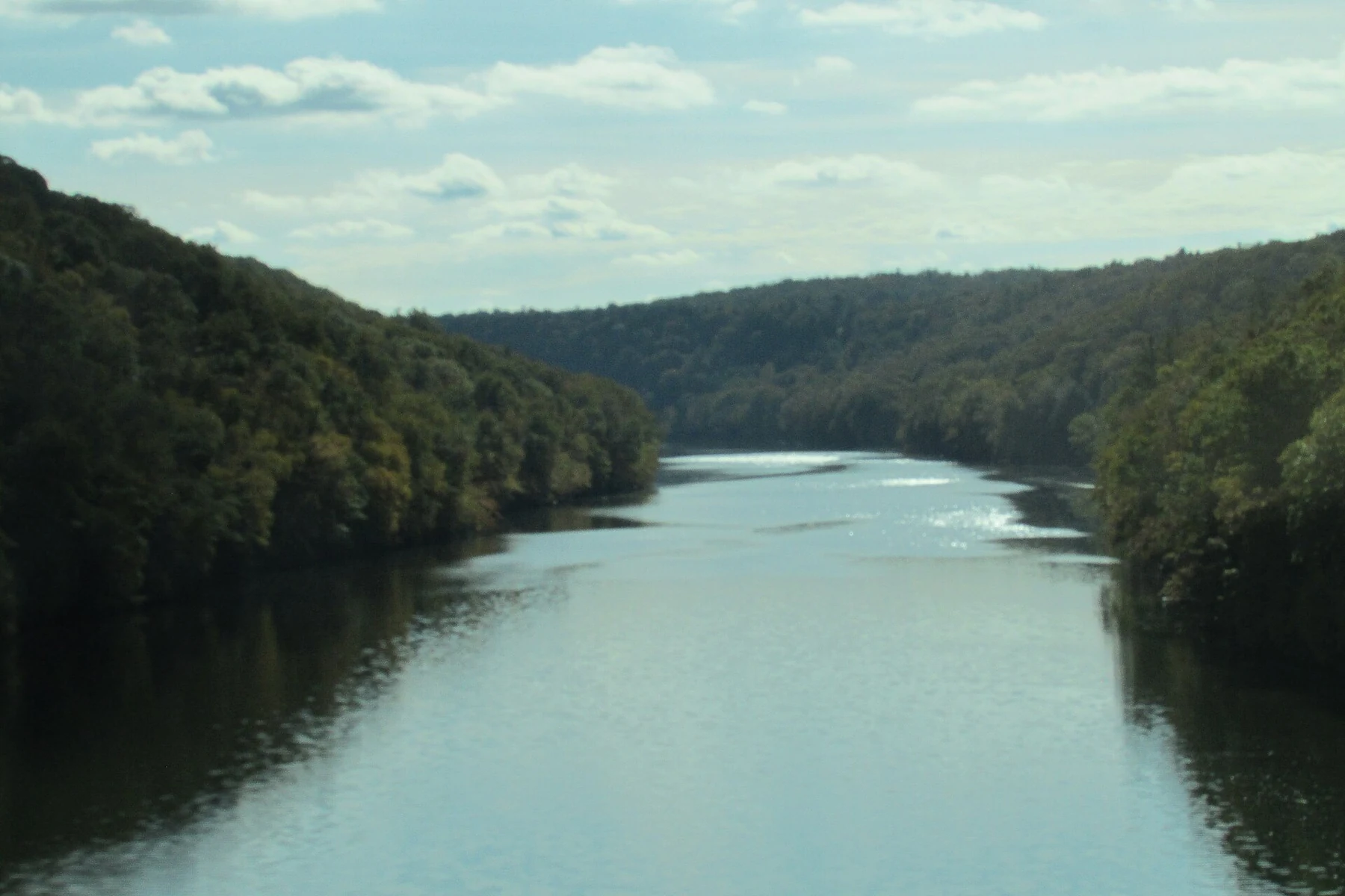 The Clarion River winding between forested hills under a partly cloudy sky.