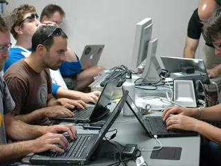 People working on laptops together at a shared table during a code sprint