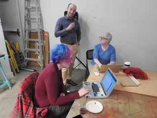 Three people working together around a table with laptops in a hackerspace