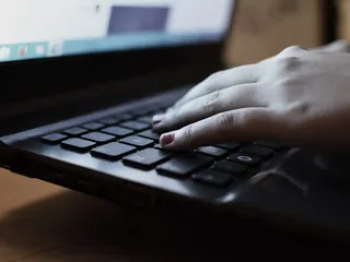 Hands typing on a laptop keyboard