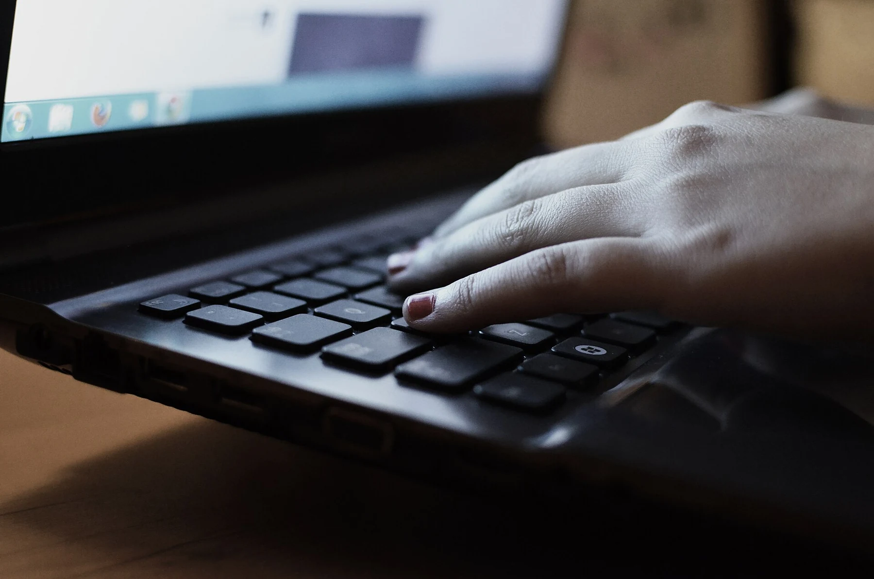 Close-up of a person's hands typing on a laptop keyboard.